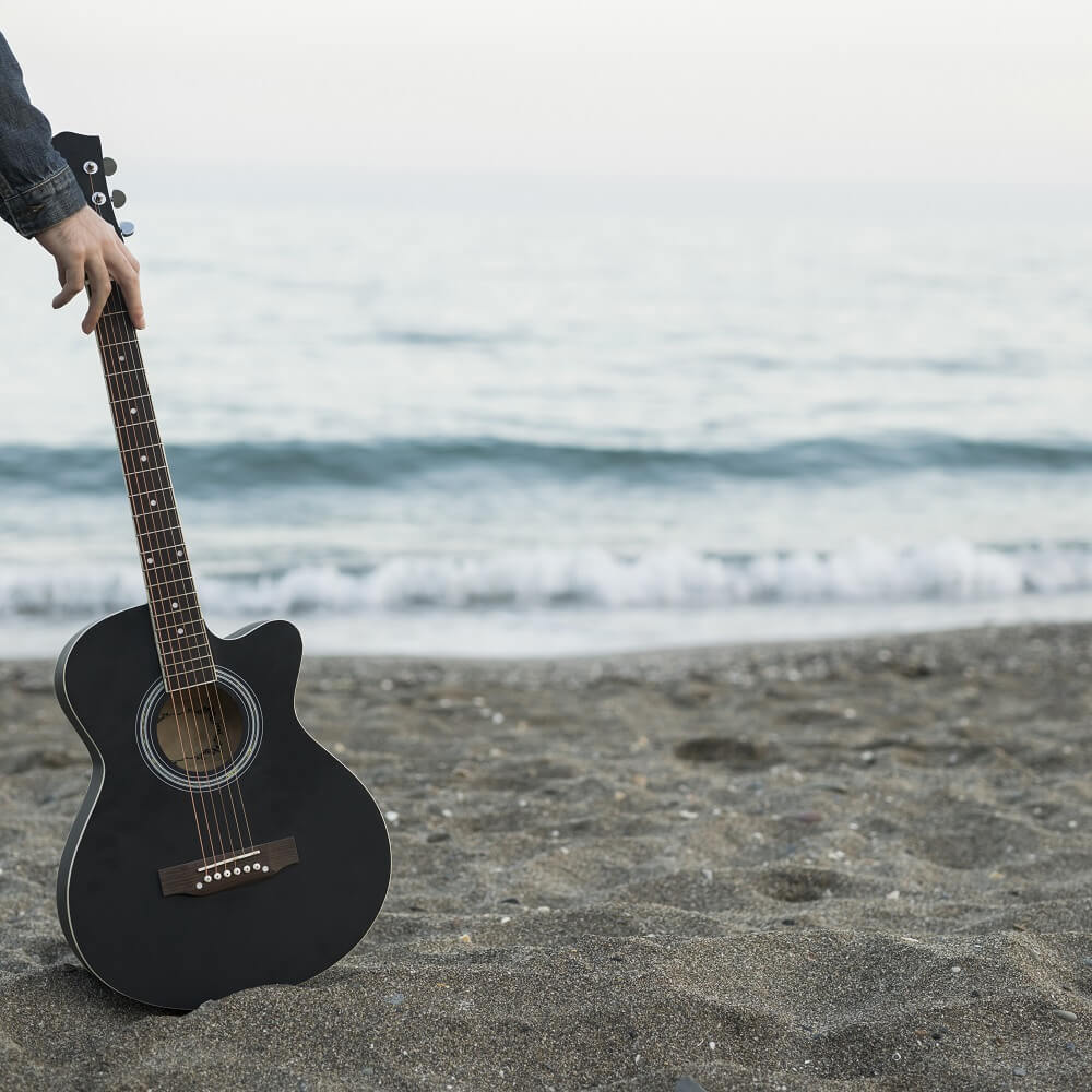 海辺でアコギを使って作曲の特訓をしている風景