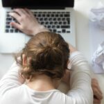ノートパソコンの上に横たわる女性。